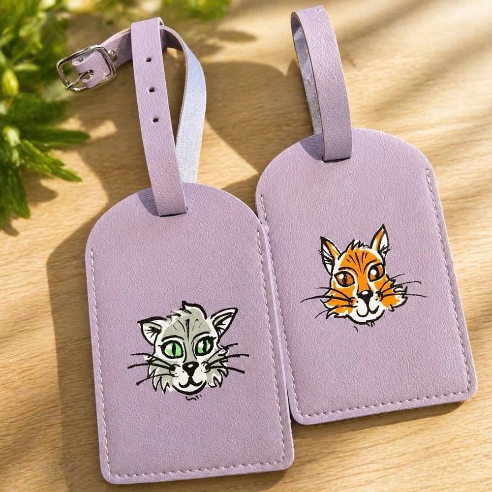 A hand-illustrated animal luggage tag held up in sunlight.